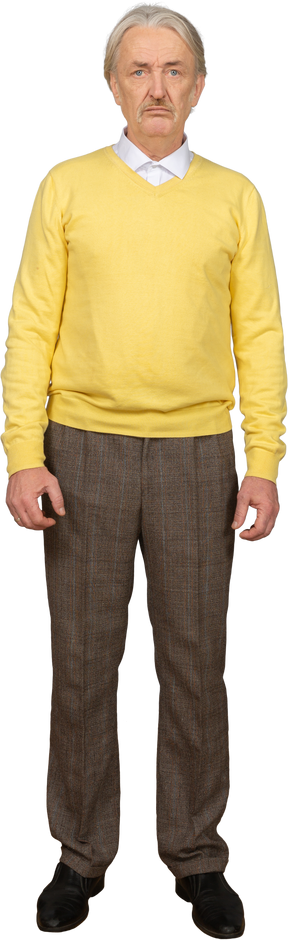 Вид спереди недовольного старика в желтом пуловере и смотрящего в камеру