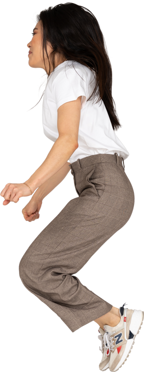 Vista lateral de una señorita saltando en calzones y camiseta doblando las rodillas