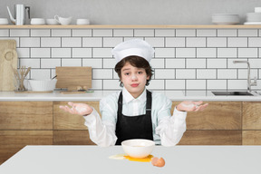 A young boy wearing a chef's hat and holding out his hands