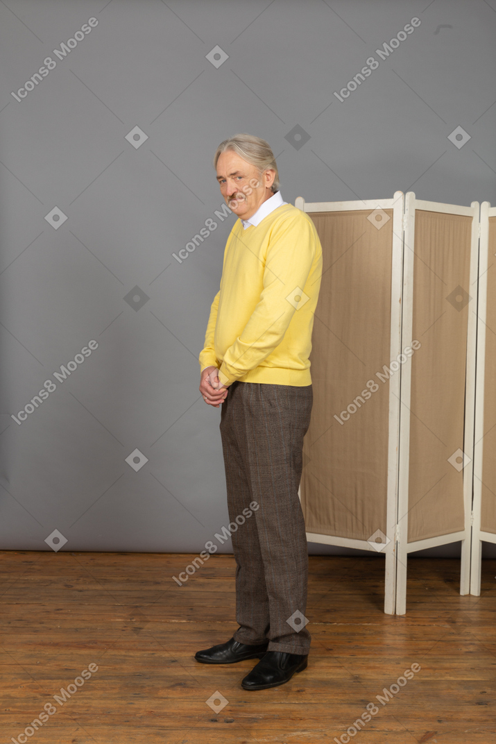 Vista de tres cuartos de un anciano sonriente confundido mirando a la cámara