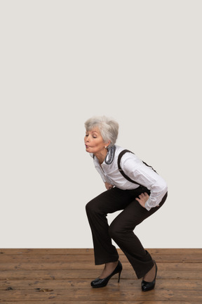 Three-quarter view of a squatting whistling old lady
