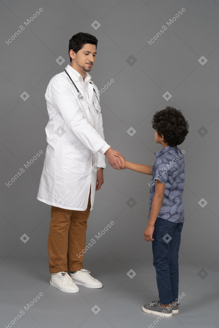 Médico e criança apertando as mãos