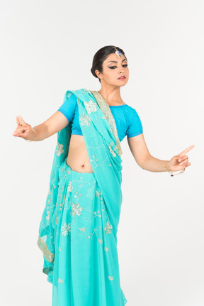 Giovane donna indiana in sari blu in piedi in posizione di danza