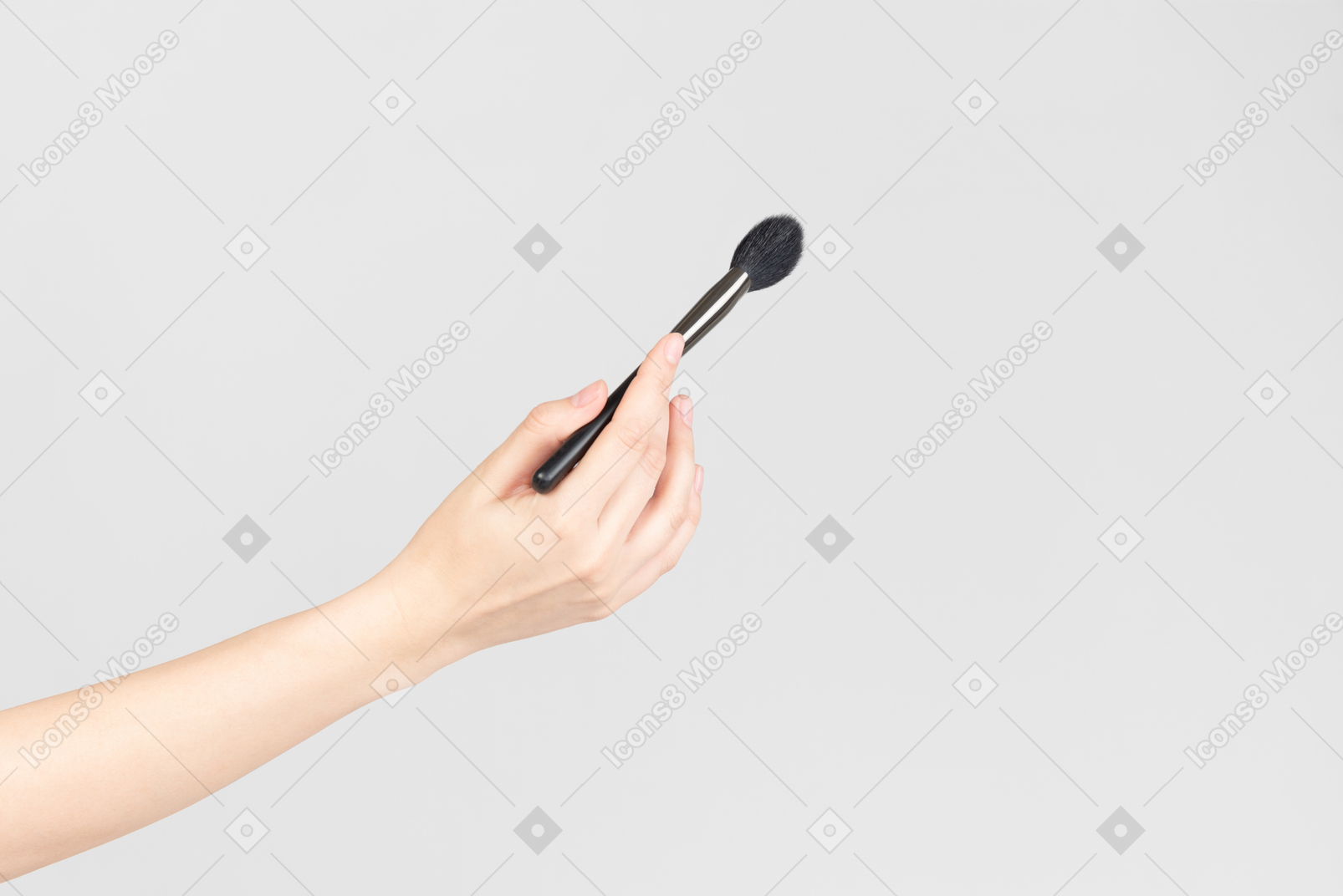 Mão feminina segurando o pincel de maquiagem de rosto
