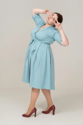 Side view of a woman in blue dress showing v sign