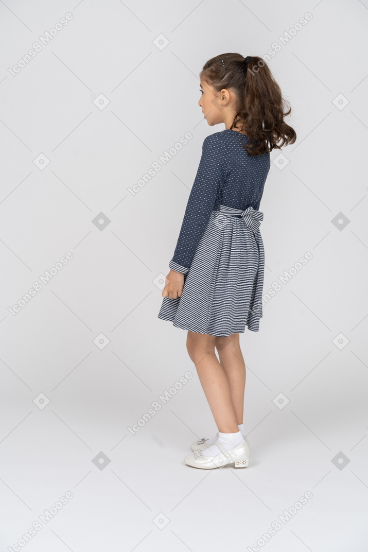 Vista trasera de tres cuartos de una niña ligeramente inclinada hacia atrás