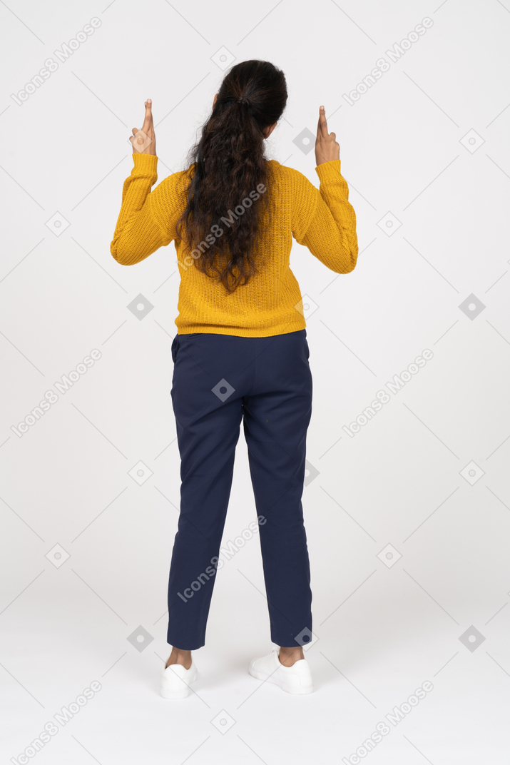 Rear view of a girl in casual clothes posing with her hands up