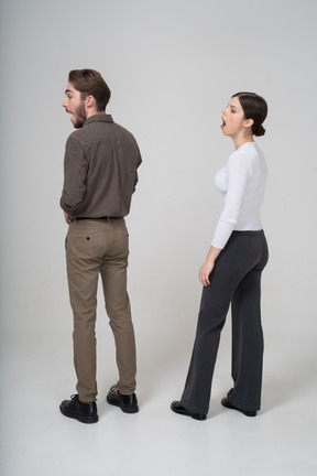 Vista posterior de tres cuartos de una pareja joven bostezo en ropa de oficina