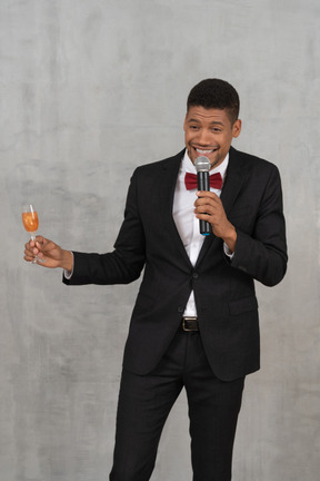 Young man with mic and flute glass talking