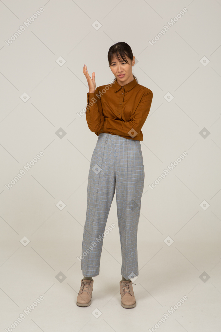Front view of a wondering young asian female in breeches and blouse raising hand