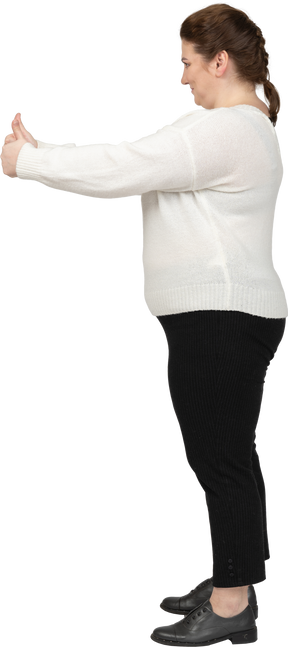 엄지 손가락을 보여주는 흰색 스웨터에 행복 한 여자