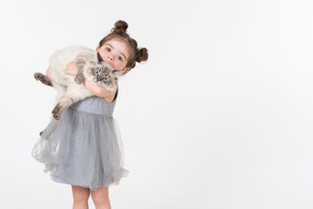Little kid girl in blue dress holding ragdoll cat