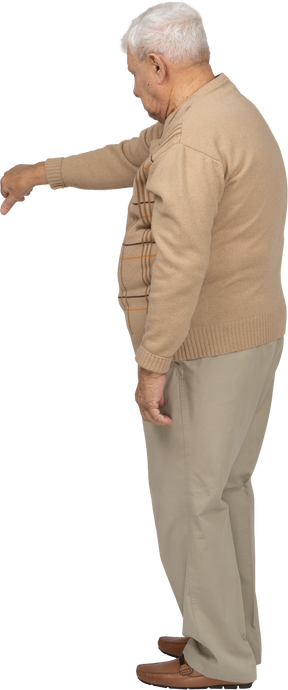 Side view of an old man in casual clothes showing thumb down