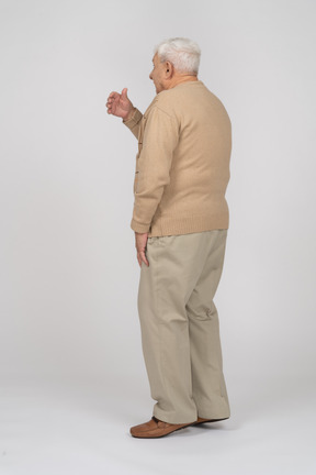 Vista lateral de un anciano con ropa informal explicando algo
