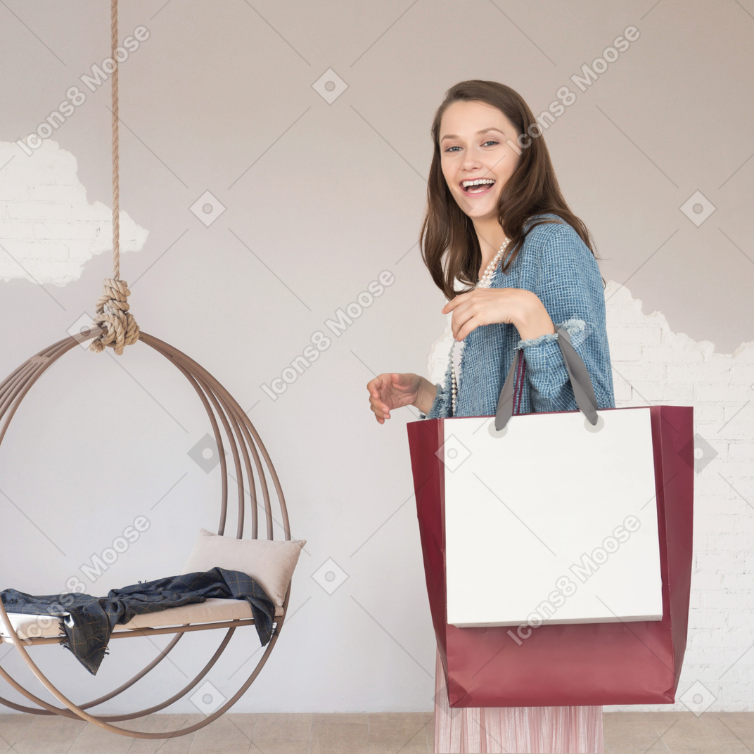 쇼핑백을 들고 방에 서 있는 여자