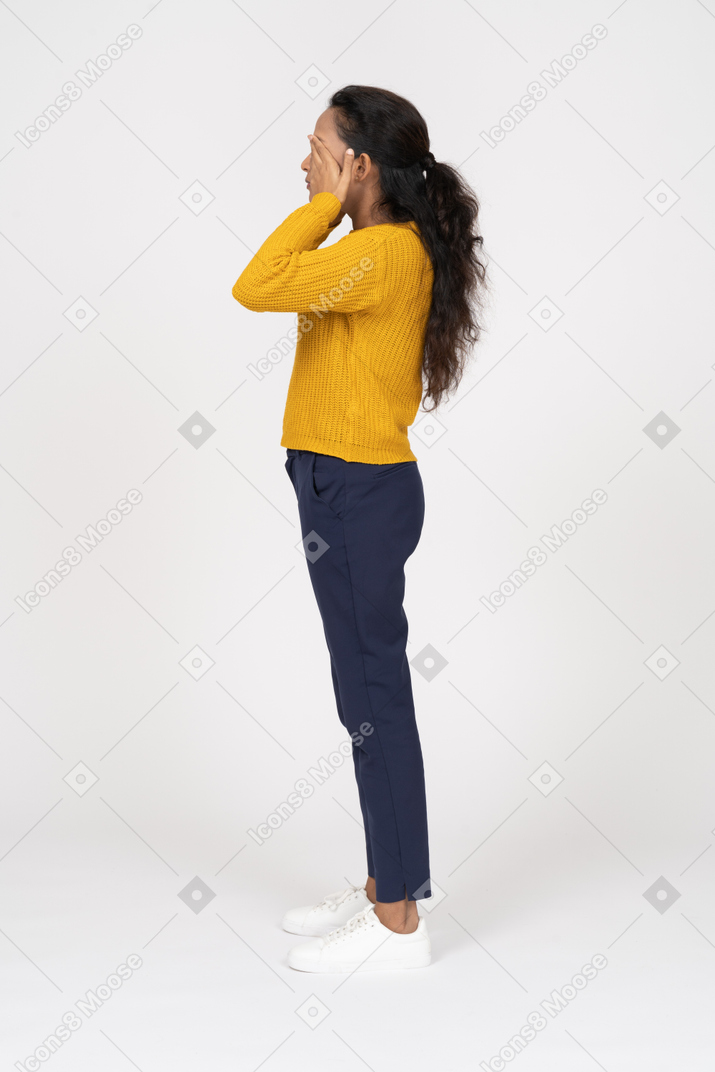 Vista lateral de uma garota com roupas casuais cobrindo os olhos com as mãos