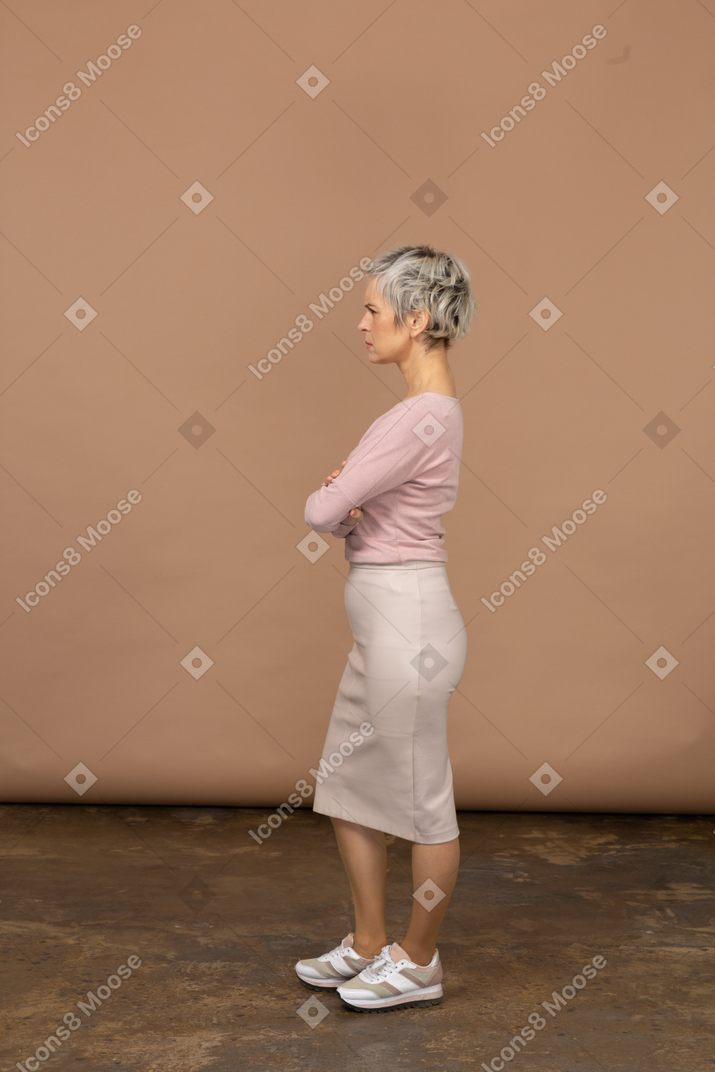 腕を組んで立っているカジュアルな服装の女性の側面図