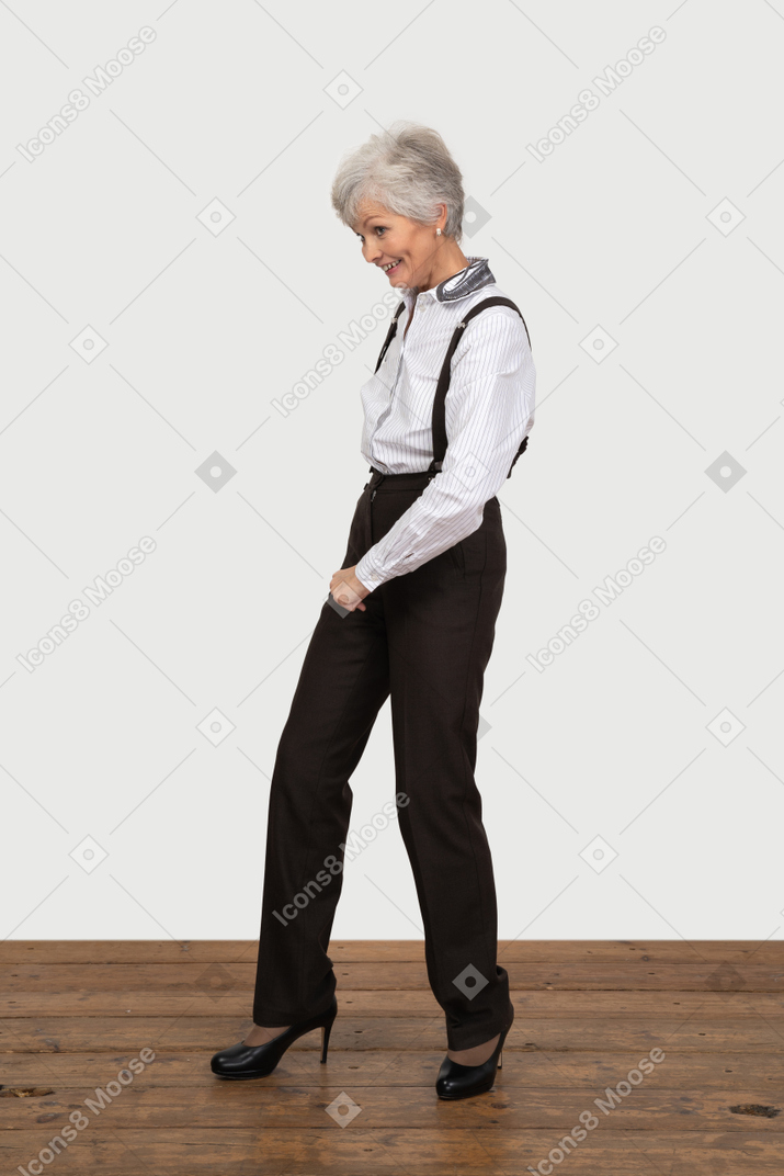 Вид в три четверти шагающей улыбающейся старушки в офисной одежде