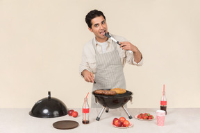 Hombre caucásico joven que tiene un sabor de barbacoa que está cocinando