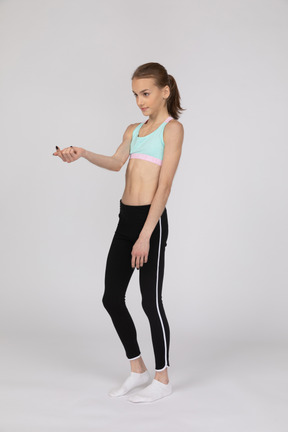 Menina adolescente em roupas esportivas fazendo gesto de aceno