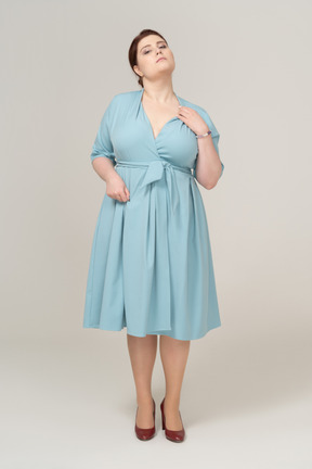 Front view of a woman in blue dress scratching her neck