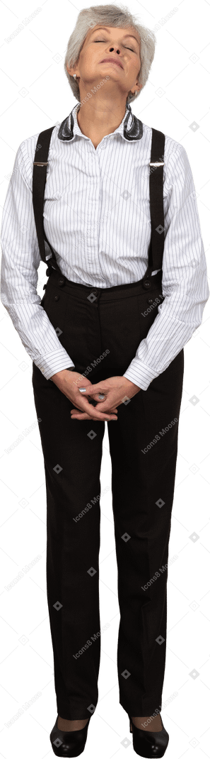 Front view of an old tired female in office clothes grimacing holding hands together