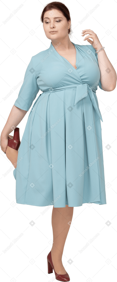 一个穿着蓝色连衣裙的女人在一条腿上保持平衡的前视图