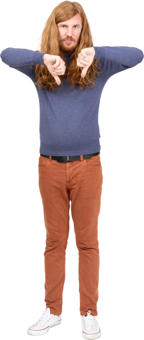 Вид спереди на молодого человека в повседневной одежде, показывающего большие пальцы вниз и смотрящего в камеру