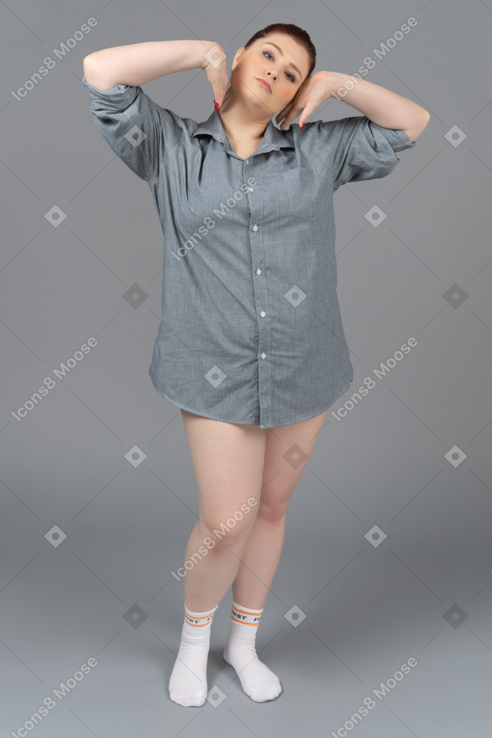 Mujer caucásica regordeta en camisa de gran tamaño estirando la espalda