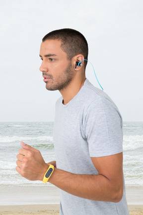 Hombre con auriculares corriendo por la costa