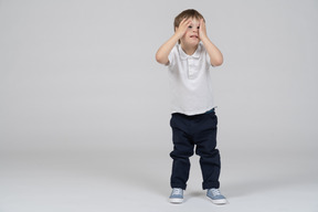 Little boy standing with hands on his face