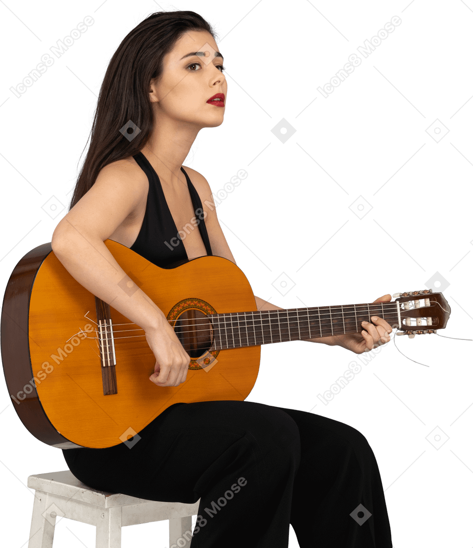 Vista de tres cuartos de una joven sentada en traje negro sosteniendo la guitarra