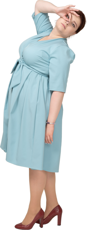 Vista lateral de uma mulher de vestido azul olhando por entre os dedos