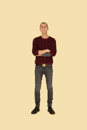 Front view of an offended young man dressed in casual clothes crossing his hands