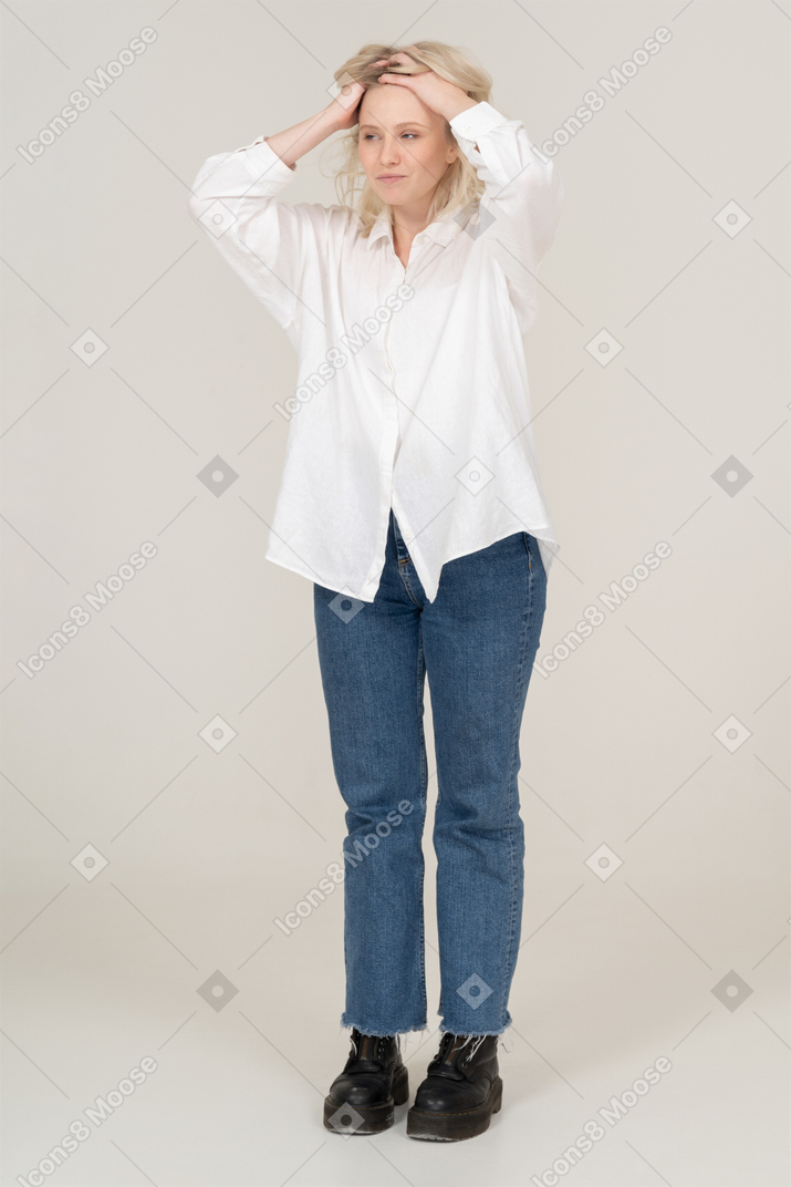 Vista de tres cuartos de una mujer rubia sorprendida levantando las manos y mirando a un lado
