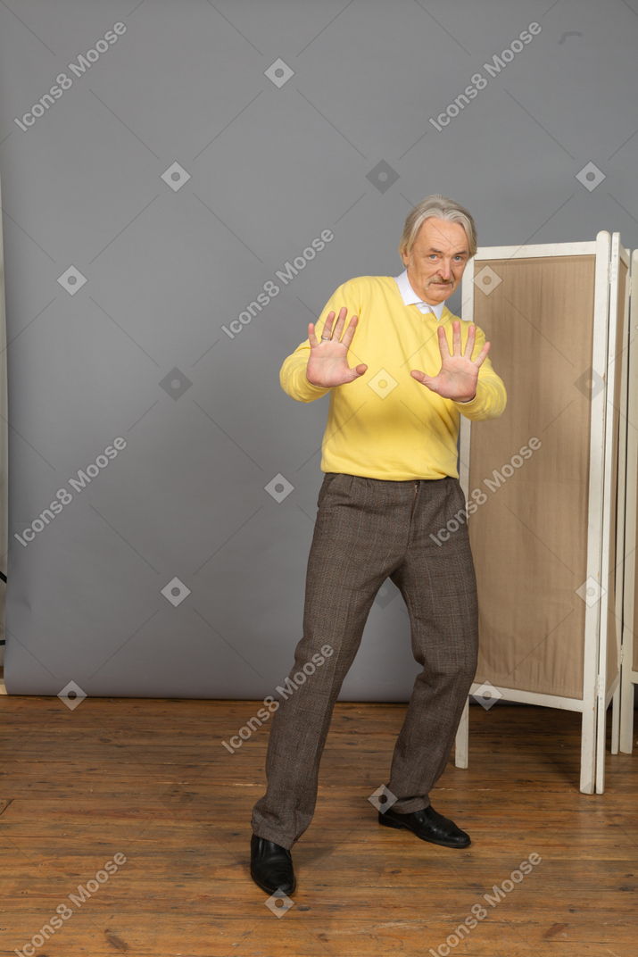 Front view of a confused old man outstretching his hands