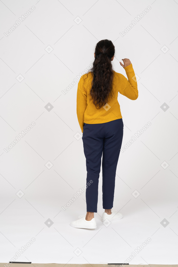 手を振っているカジュアルな服を着た女の子の背面図