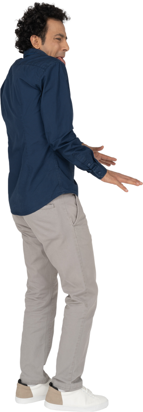 Vista laterale di un uomo in abiti casual che mostra la lingua e gesticola