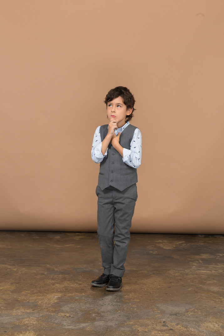 Front view of a thoughtful boy in grey suit