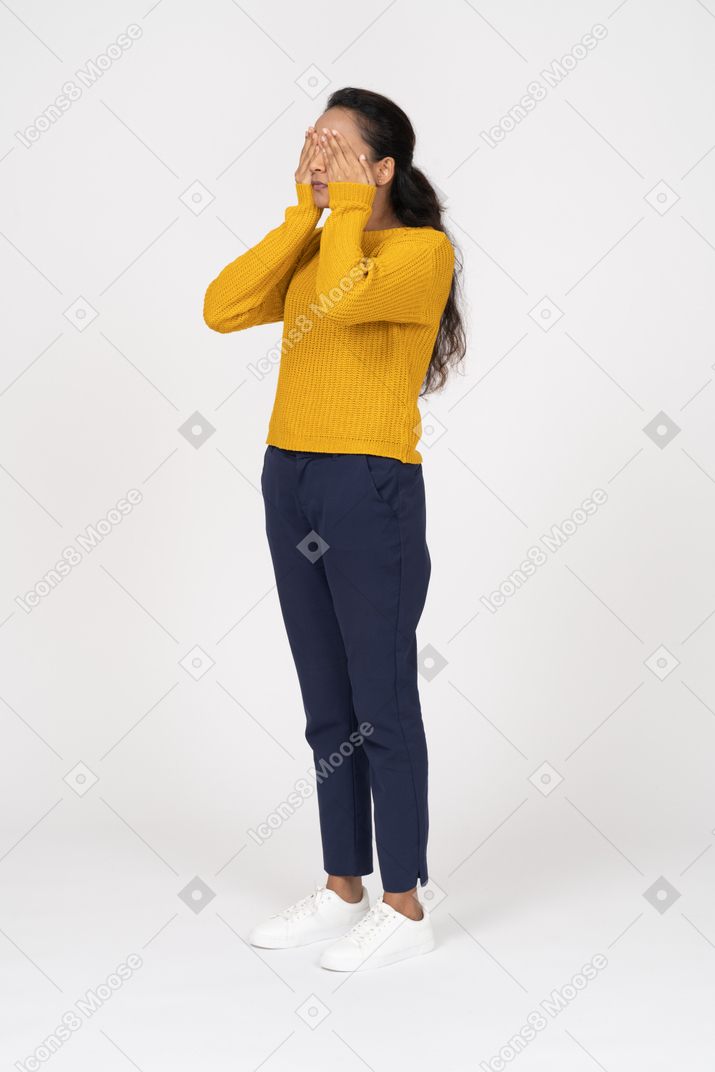 一个穿着休闲服的女孩用手遮住眼睛的前视图