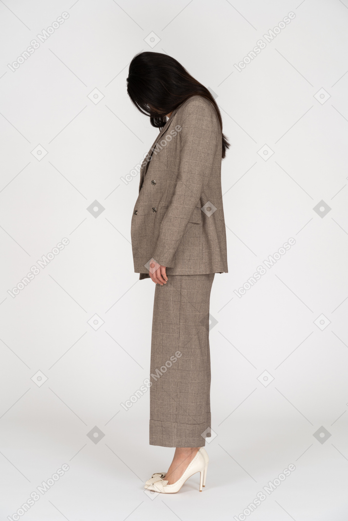 Vue latérale d'une jeune femme en costume marron regardant vers le bas