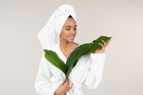 Femme noire en peignoir blanc et une serviette de tête profitant de sa routine de soins de la peau