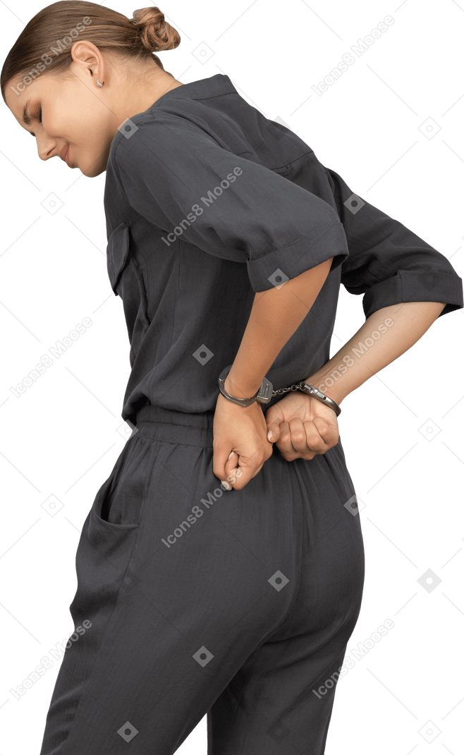 Трехчетвертный вид сзади страдающей молодой женщины в комбинезоне с наручниками