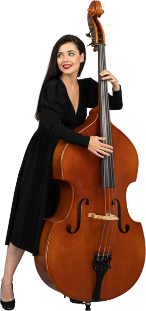 Vista frontale di una giovane donna sorridente in abito nero che suona il suo contrabbasso