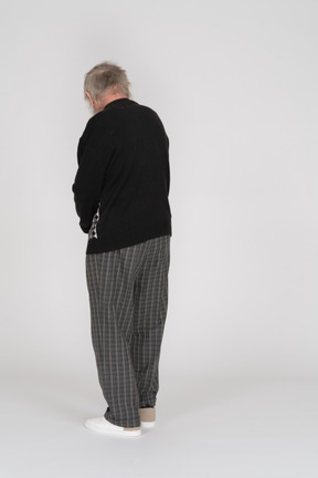 Back view of old man standing and looking down