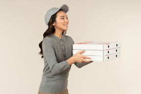 Young asian pizza delivery girl holding pizza boxes