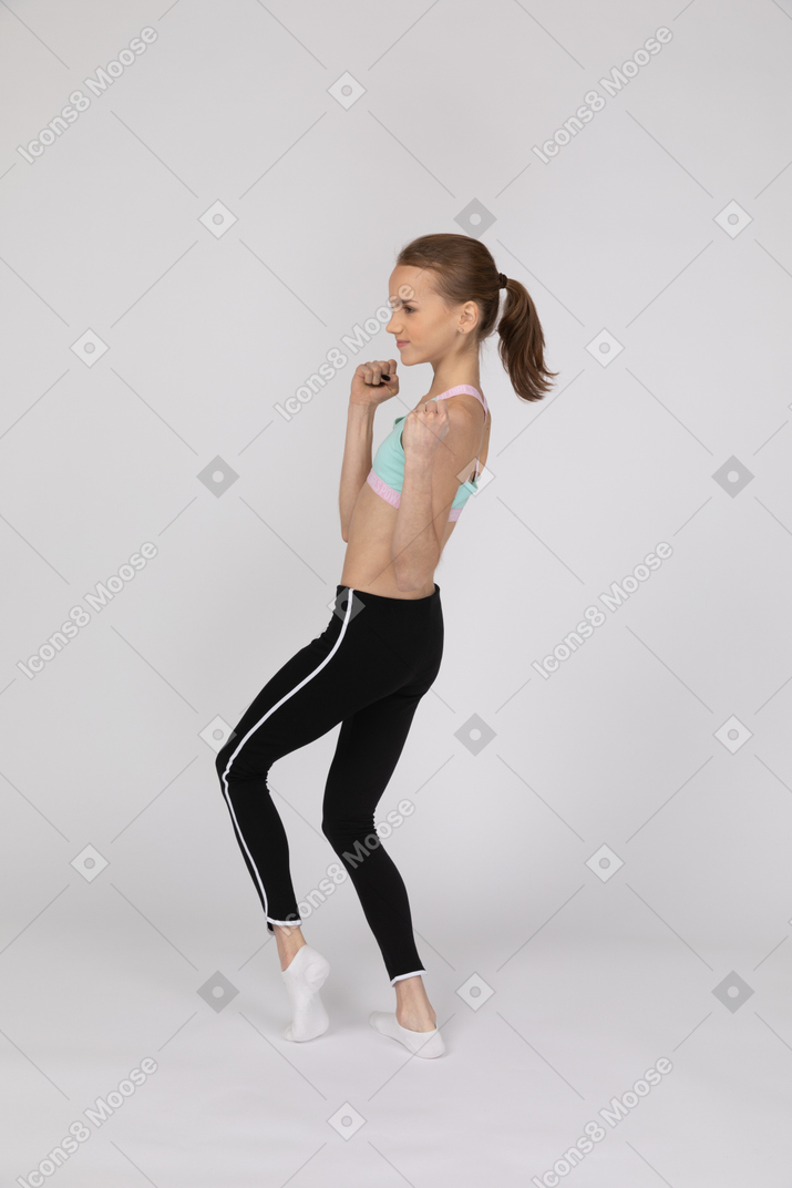 Una adolescente con ropa deportiva celebrando con los puños cerrados