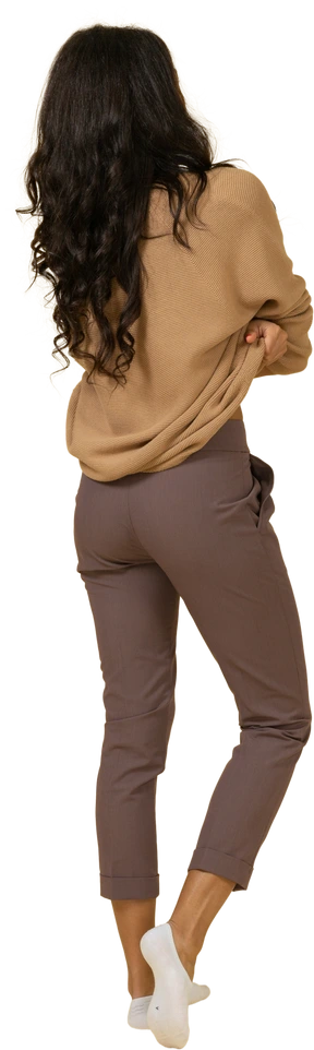 Three-quarter back view of a dark-skinned young female taking off her pullover