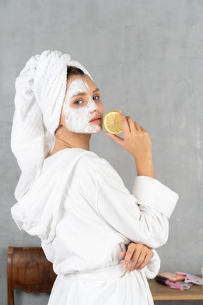 Вид сзади на женщину в халате, держащую лимон