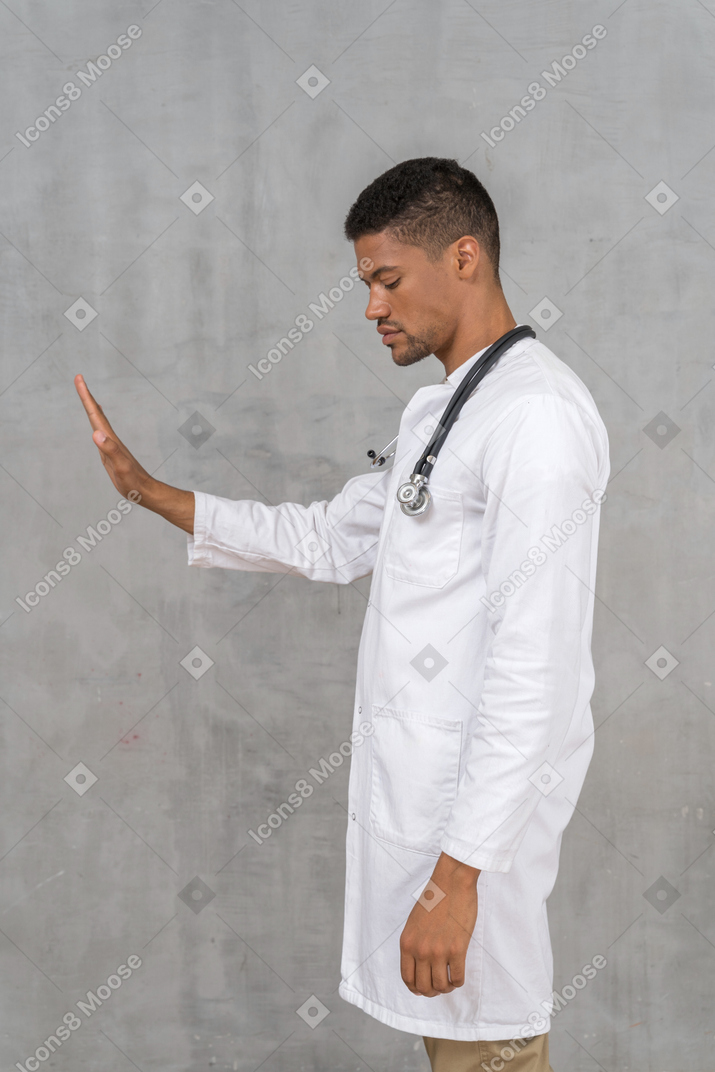 Vista lateral de un médico masculino que muestra la mano de parada